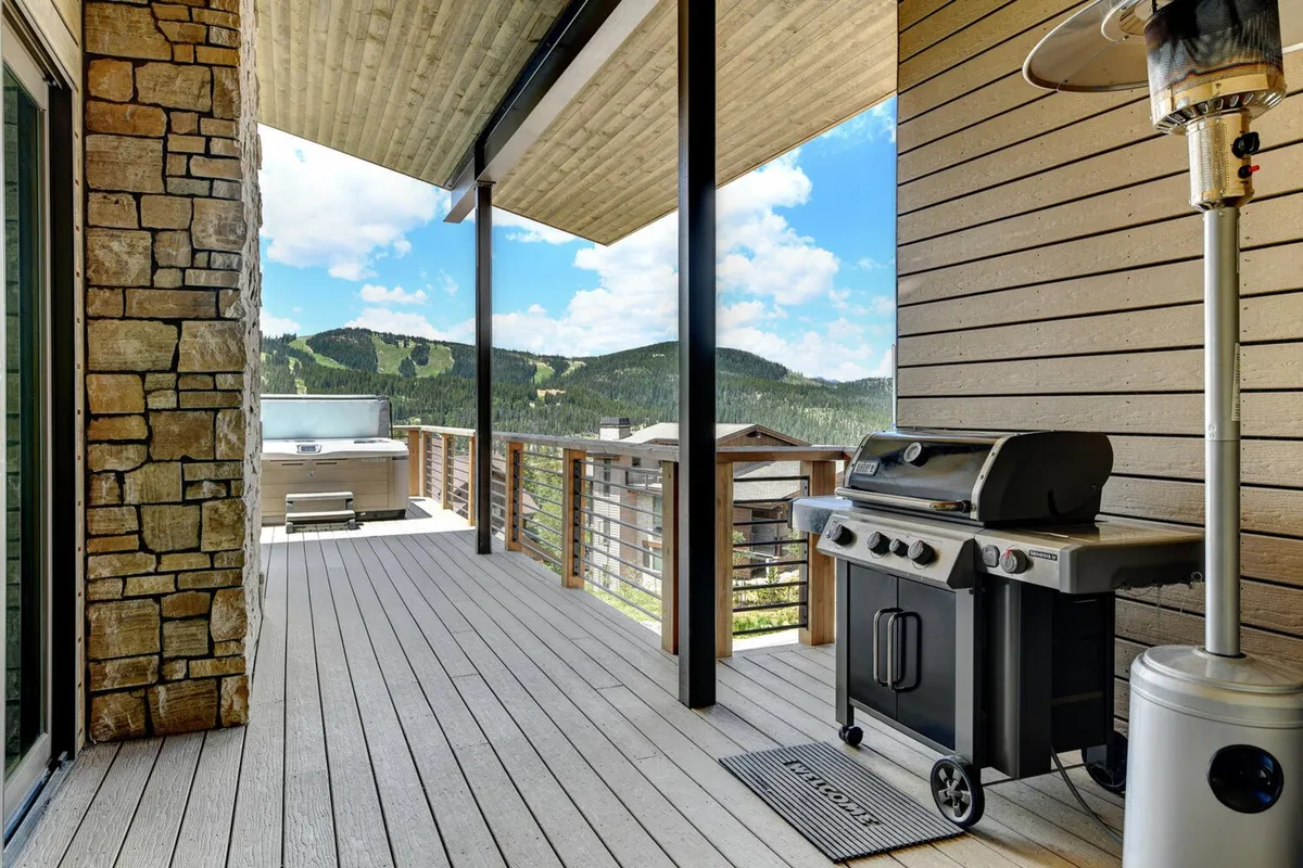 An outdoor deck features a professional grill, comfortable seating, and a panoramic mountain view. The setup is perfect for barbecuing, outdoor dining, and social gatherings, with the grill prominently placed for easy access and hosting.