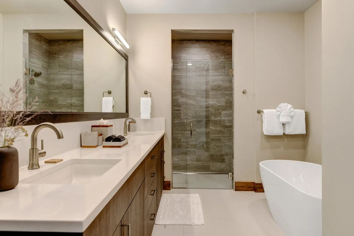 A luxurious bathroom with a freestanding soaking tub, dual sinks, a large mirror, and a glass shower enclosure. The space exudes spa-like tranquility, ideal for unwinding after a long day.
