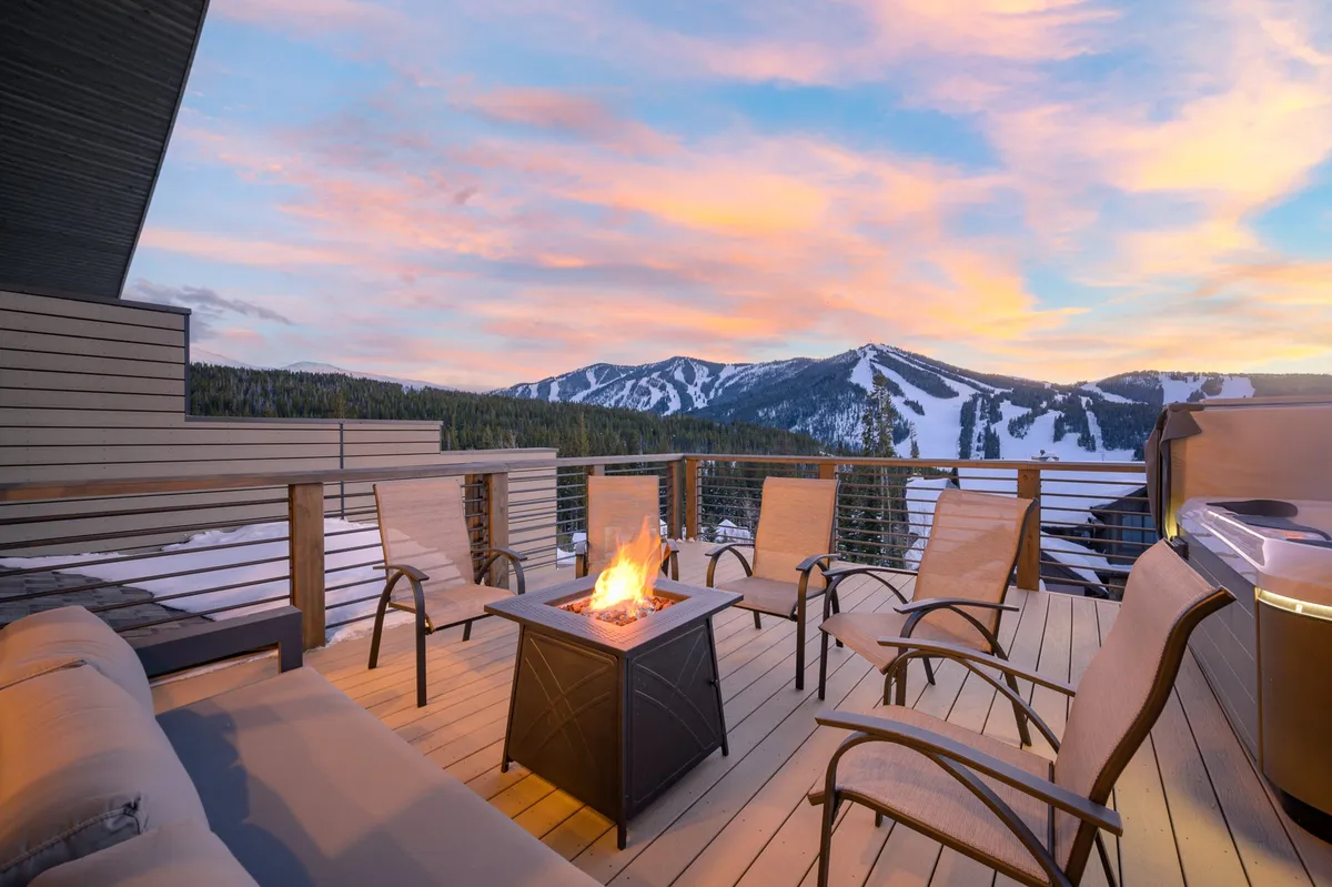 An inviting exterior scene featuring a fire pit with outdoor seating, set against a dramatic mountain view at sunset. The setting is ideal for relaxing or socializing after an active day, evoking the enjoyment of Colorado’s mountain air and natural beauty.