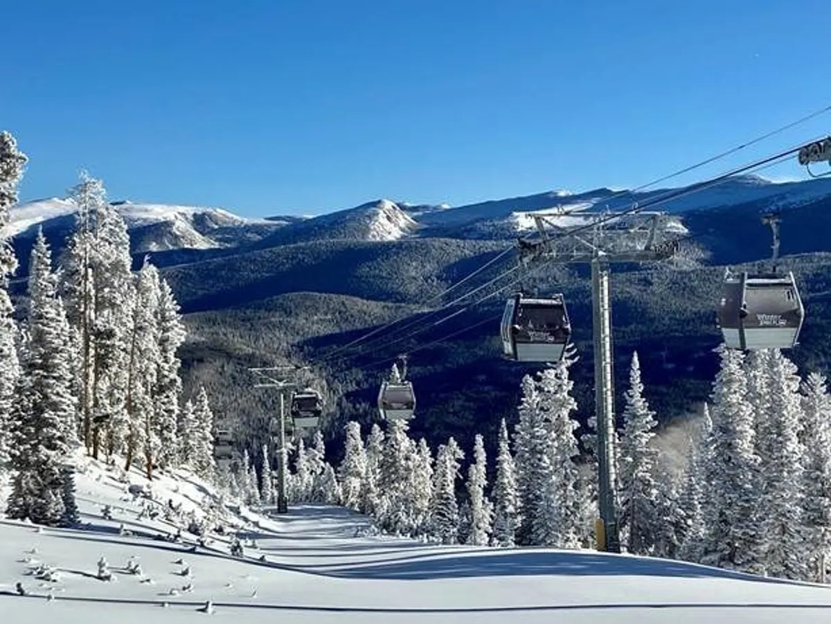 A sweeping exterior scene featuring ski lift gondolas moving above snow-covered trees with a dramatic mountain landscape in the background. The slopes are visible, with inviting powder and scenic vistas, creating a sense of excitement and adventure.
