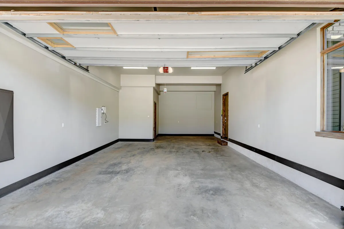 A spacious and tidy garage with ample room for vehicle parking and storage, featuring clean walls and a visible doorway leading into the home. The garage is well-lit and organized, suggesting plenty of space for outdoor gear and easy transitions from adventure to relaxation.